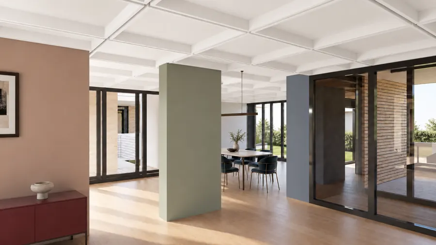 Eine Wohnung auf einer Ebene: unter einer weissen Rippendecke gliedern farbige Wandscheiben — Terrakotta, Salbeigruen, Blaugrau — den durchgehenden Raum; in der Mitte ein Esstisch mit Stuehlen vor einer raumhohen Glaswand, rechts Glastueren zum Hof.