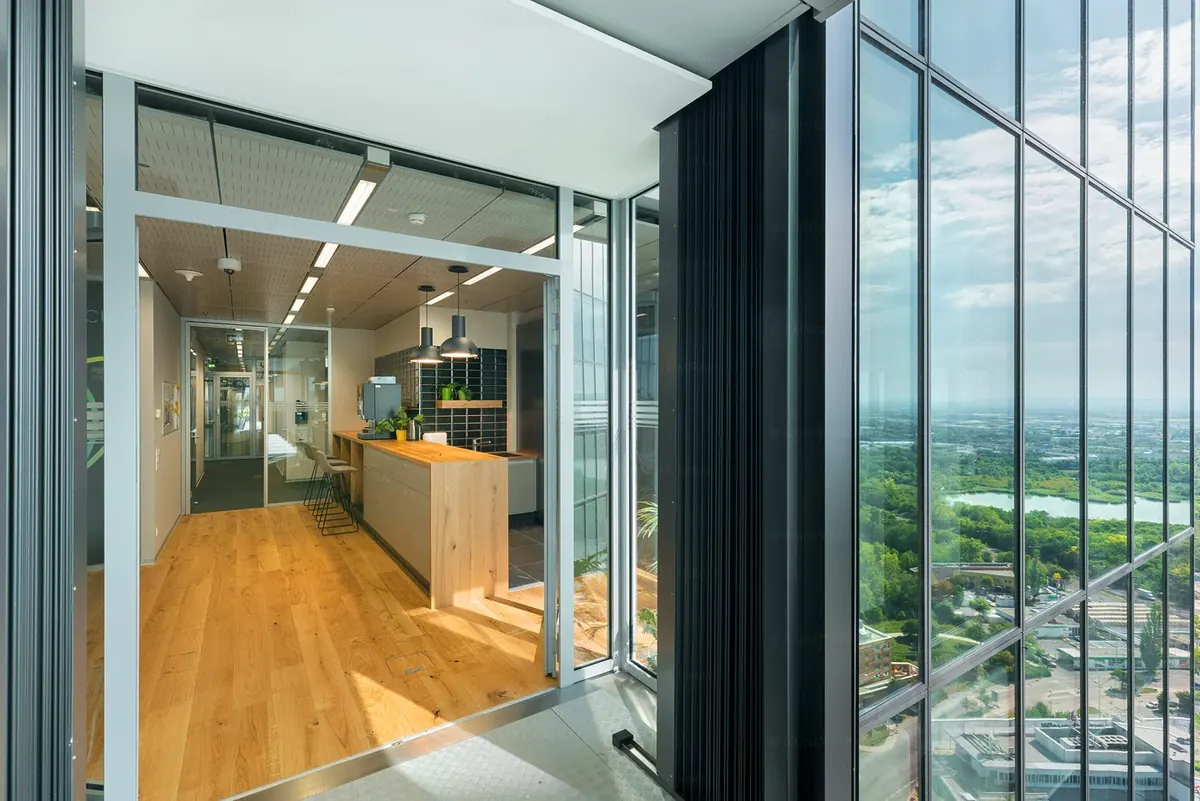 Bürogeschoss in einem Hochhaus: Theke aus Holz, Glaswände, raumhohe Fenster mit Blick über Wien
