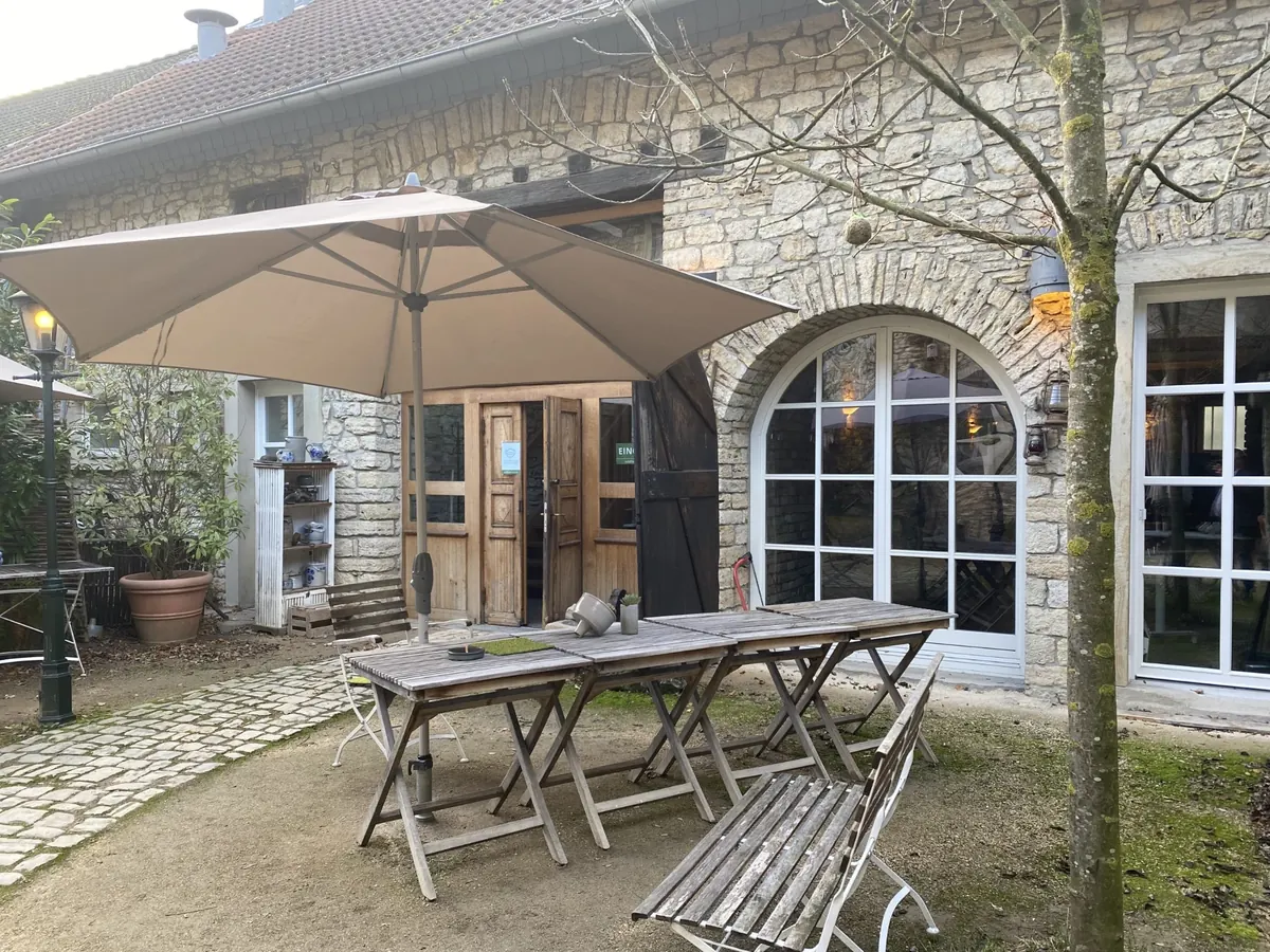 Hof des Alten Gutshofs in Ingelheim mit Sonnenschirm, Holztischen und Rundbogenfenstern